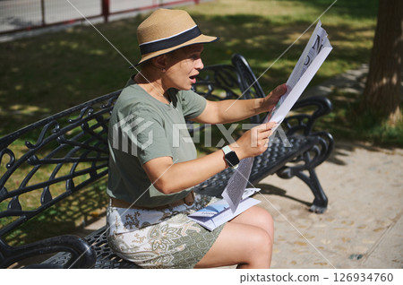 Woman Reading a Newspaper on a Bench in a Park Under the Sun 126934760
