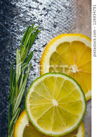 Fresh fish fillet, garnished with lemon and herbs, on a dark background, ready to cook 126934791