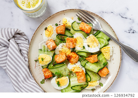 Delicious salmon and egg salad served on a plate with fresh cucumber and herbs for a healthy meal at lunchtime Delicious salmon and egg salad served on a plate with fresh cucumber and herbs for a healthy meal at lunchtime 126934792