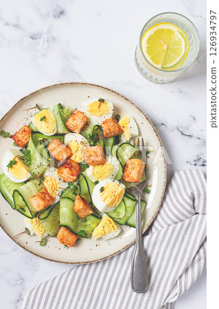 Delicious salmon and egg salad served on a plate with fresh cucumber and herbs for a healthy meal at lunchtime Delicious salmon and egg salad served on a plate with fresh cucumber and herbs for a healthy meal at lunchtime 126934797