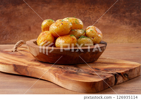 Baked new potatoes, with butter and dill, on a wooden plate, homely, rustic, no people, 126935114