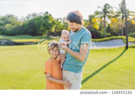 Father, older son, and newborn baby on a meadow in the park. Family spending quality time together in nature. Parenthood, love, and family bond concept 126935130