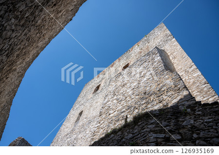 Visitors admire the impressive Donjon Tower of Rabi Castle, showcasing its rugged stone structure against the clear blue sky. The historical significance of the site draws many explorers. Visitors admire the impressive Donjon Tower of Rabi Castle, showcasing its rugged stone structure against the clear blue sky. The historical significance of the site draws many explorers. 126935169