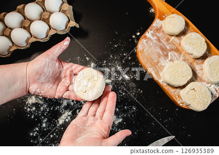 Process of making syrniki. Form round syrniki from curd dough. Top view on black surface. Russian cuisine. 126935389
