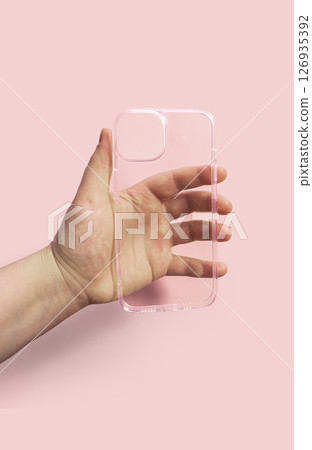 Clean transparent phone case displayed in hand against light pink backdrop, Modern and comfortable design Clean transparent phone case displayed in hand against light pink backdrop, Modern and comfortable design 126935392