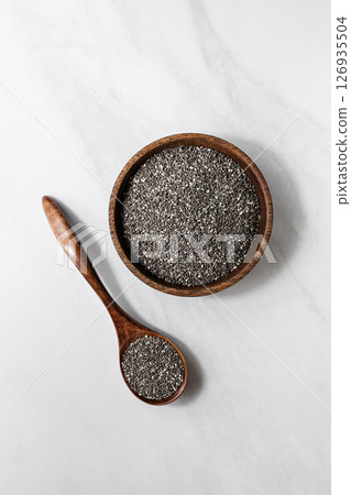 Close-up of chia seeds in a glass jar with a wooden spoon. Healthy superfood concept Close-up of chia seeds in a glass jar with a wooden spoon. Healthy superfood concept 126935504