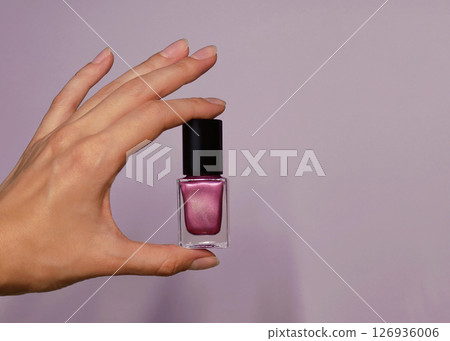 Pink violet nail polish in a woman's hand close up. Background banner with copy space for text Pink violet nail polish in a woman's hand close up. Background banner with copy space for text 126936006