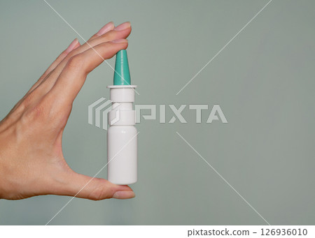 A nasal spray in a woman's hand close up. Background banner with copy space for text A nasal spray in a woman's hand close up. Background banner with copy space for text 126936010