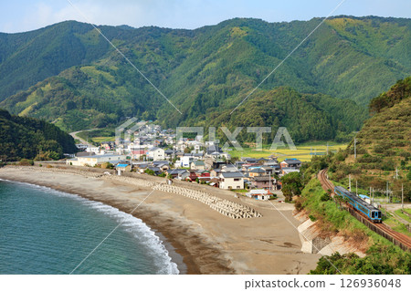 A diesel train on the Tosan Line runs along the deep blue coastline of Tosa Bay. 126936048