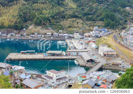 A diesel train on the Kisei Main Line runs alongside the calm waters of Nikishima Port. 126936063