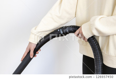 Close-up of a woman cleaning her apartment with a professional vacuum cleaner. Close-up of a woman cleaning her apartment with a professional vacuum cleaner. 126937450