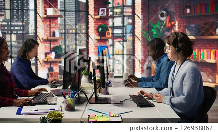 Call center agent helping customers regain access to accounts, resetting passwords. Employee in customer center workspace assisting clients needing help, providing helpful solutions, camera B 126938062