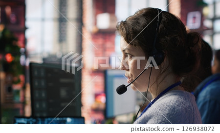 Call center agent uses artificial intelligence to enhance customer interactions and resolve inquiries efficiently. Woman in customer service office using AI communication technologies, camera A 126938072
