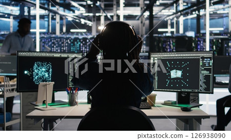 Data center engineer implements AI virtualization frameworks to optimize server clusters. Server hub IT professional doing artificial intelligence predictive analysis, camera A Data center engineer implements AI virtualization frameworks to optimize server clusters. Server hub IT professional doing artificial intelligence predictive analysis, camera A 126938090