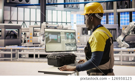Engineer overseeing solar panel production lines equipment using PC software. Worker maintaining photovoltaic assembly systems in automated industry 4.0 factory using computer, camera A Engineer overseeing solar panel production lines equipment using PC software. Worker maintaining photovoltaic assembly systems in automated industry 4.0 factory using computer, camera A 126938123