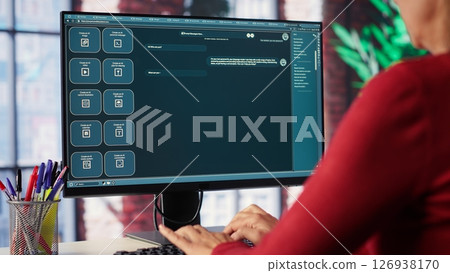Professional person engaging with an AI chatbot on a computer screen, exploring power of digital assistance through artificial intelligence. Solutions for assistance at desktop. Camera A. 126938170