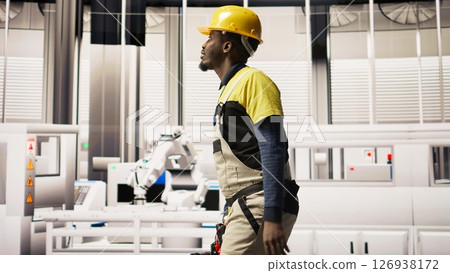 Technician holding toolbox walking in factory, overseeing solar panel production lines equipment. Engineering expert maintaining photovoltaic assembly systems in automated industrial plant, camera A 126938172