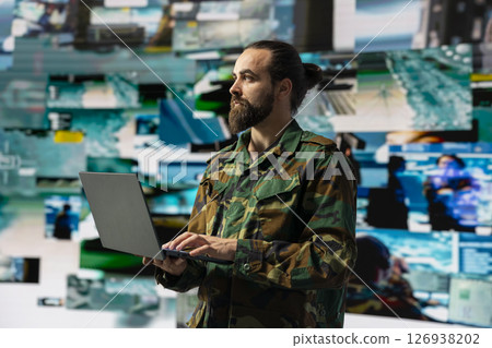 Male soldier operates in a virtual war zone using digital technology and threat detection tools, showcasing modern military strategy. Ensuring secure communications in active operations. Male soldier operates in a virtual war zone using digital technology and threat detection tools, showcasing modern military strategy. Ensuring secure communications in active operations. 126938202