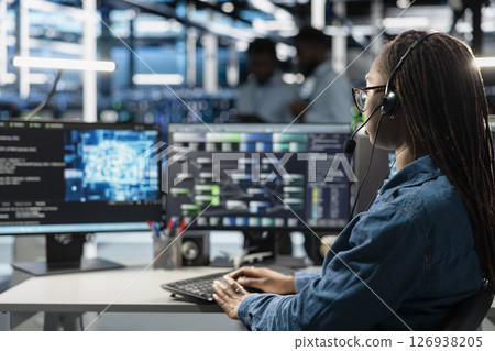 Data center support expert talking in headset microphone, supporting engineering team doing equipment maintenance. Employee in server farm coordinating technicians using mic 126938205