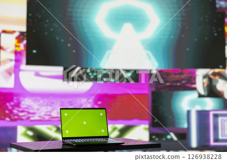 Laptop running isolated mockup screen surrounded by funky visual art clips, glowing in the dark and creating a clubbing atmosphere. Nightlife ambiance with modern beats and lights. 126938228