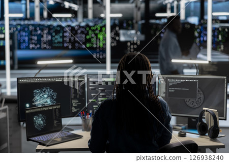 Data center software developer uses AI visualization tool to oversee automated repetitive tasks. Server room worker adapting infrastructure systems based on data analytics graphs using PC 126938240