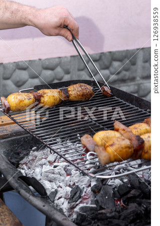 Chef grilling potatoes and bacon on barbecue grill outdoors 126938559