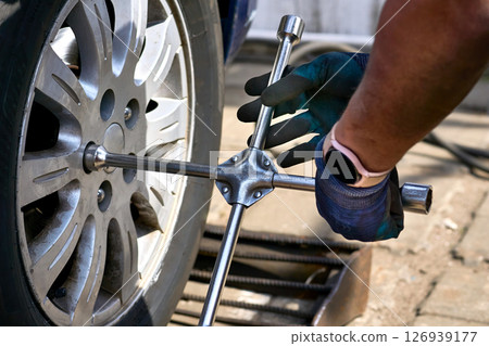Wheel repair mounting.Worker tightens nuts on wheel.Service for repair of car Wheel repair mounting.Worker tightens nuts on wheel.Service for repair of car 126939177