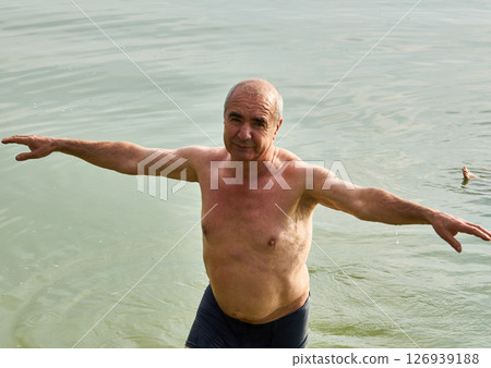 Funny elderly pensioner loves to swim in the summer river 126939188