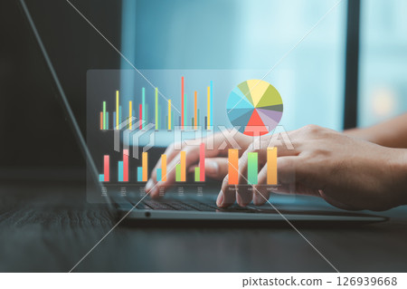 Colorful chart graphs and pie diagram hovering over hands typing on laptop for business analytics Colorful chart graphs and pie diagram hovering over hands typing on laptop for business analytics 126939668