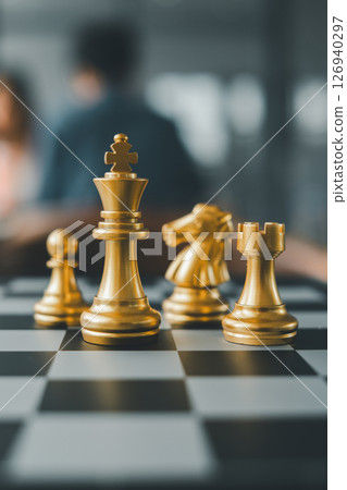 Close-up of golden chess pieces on a chessboard, highlighting strategy and competition in a blurred background setting. Close-up of golden chess pieces on a chessboard, highlighting strategy and competition in a blurred background setting. 126940297
