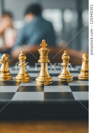 Close-up of gold chess pieces on a board, capturing a strategic moment in a contemporary environment. 126940301