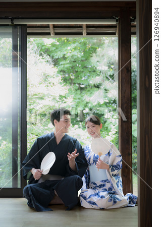 A man and a beautiful woman in yukata relaxing on a veranda surrounded by beautiful greenery. Image of a hot spring after a trip or a stay at a ryokan. Vertical A man and a beautiful woman in yukata relaxing on a veranda surrounded by beautiful greenery. Image of a hot spring after a trip or a stay at a ryokan. Vertical 126940894