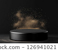Black circular platform with golden powder against a dark background 126941021