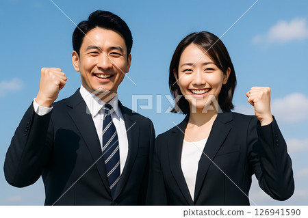 Smiling male and female businessmen in suits making a fist pump 126941590