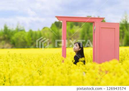 一名女子在盛開的油菜花田裡觀光（粉紅色門） 126943574