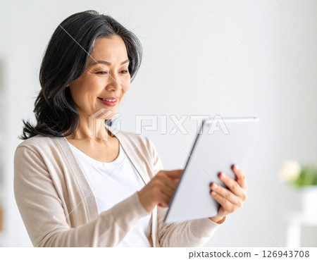 一位中年婦女微笑著操作平板電腦 126943708