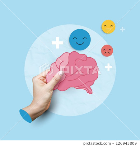 Medical concepts. hand holding brain paper cut with happy, sad, and neutral emoticons representing mental health, emotional balance, psychology, and mood regulation on blue background. 126943809