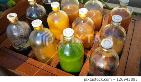 Colorful Bottles of traditional natural organic medicine locally called jamu, Displayed in Wooden Case on a Sunny Day Colorful Bottles of traditional natural organic medicine locally called jamu, Displayed in Wooden Case on a Sunny Day 126943885