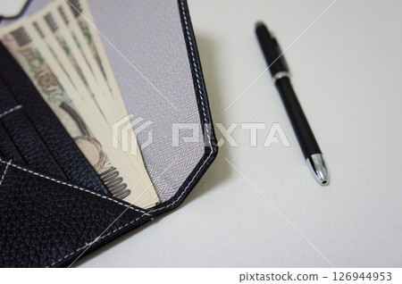 錢包。桌上放著一個長錢包和一萬日元鈔票。 錢包。桌上放著一個長錢包和一萬日元鈔票。 126944953