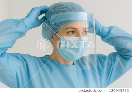 A female doctor wearing a face shield in a medical setting 126945733