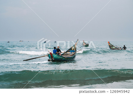 Vietnamese fishermen men on wooden traditional boats in the sea at fishing village in Vietnam Vietnamese fishermen men on wooden traditional boats in the sea at fishing village in Vietnam 126945942