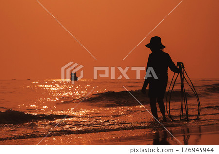 Silhouette of Vietnamese woman on the shore of sea with ship in a fishing village in the morning at sunrise in Vietnam 126945944