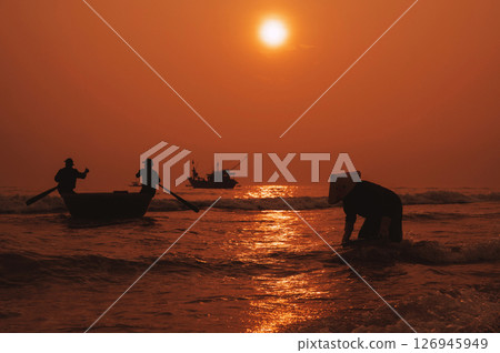 Silhouettes of Vietnamese fishermen in a round basket boat and a woman in a straw hat in a fishing village in the morning at sunrise in Vietnam 126945949