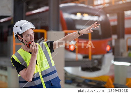 Engineer railway foreman working control order with radio in railway station, Engineer wearing safety uniform and safety helmet in work. Engineer railway foreman working control order with radio in railway station, Engineer wearing safety uniform and safety helmet in work. 126945988