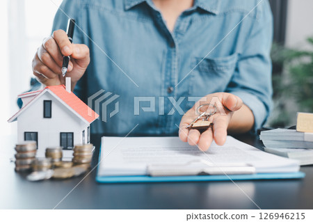 Female real estate broker presenting and advised to model home, building project detail in office, sign purchase sales application contract, agreements concerned mortgage loan offer and insurance. 126946215