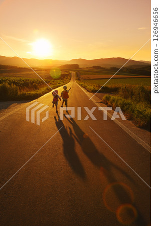 Brother and sister walking down a road at dusk Brother and sister walking down a road at dusk 126946656