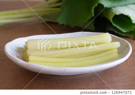 Raw butterbur and boiled butterbur on a white plate Raw butterbur and boiled butterbur on a white plate 126947071