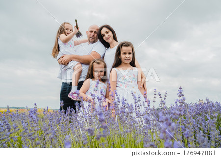 A mother in a white dress is hugging her husband, who is holding a cute little girl A mother in a white dress is hugging her husband, who is holding a cute little girl 126947081