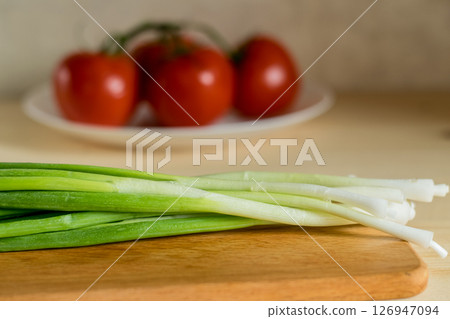 Close-up of young onions on a wooden kitchen board 126947094