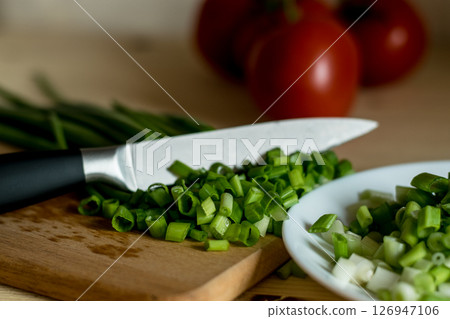 On a snow-white plate lies freshly chopped green onion On a snow-white plate lies freshly chopped green onion 126947106